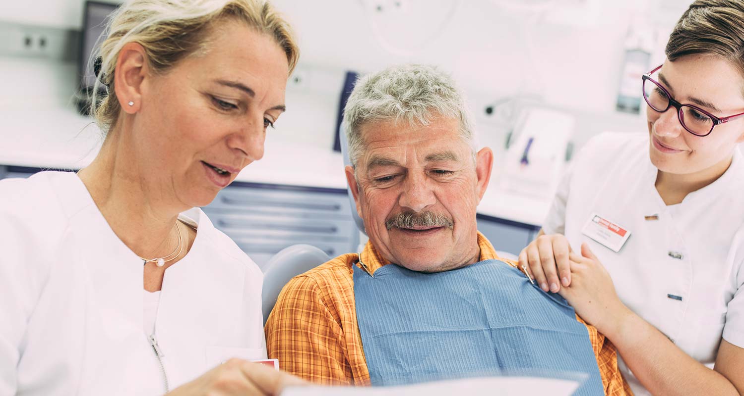 Dr. Carmen Pohl und Mitarbeiterin erklären Patienten etwas über Erkrankungen des Zahnfleischs