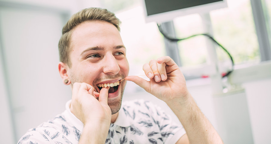 Patient reinigt sich die Zahnzwischenräume mit Zahnseide