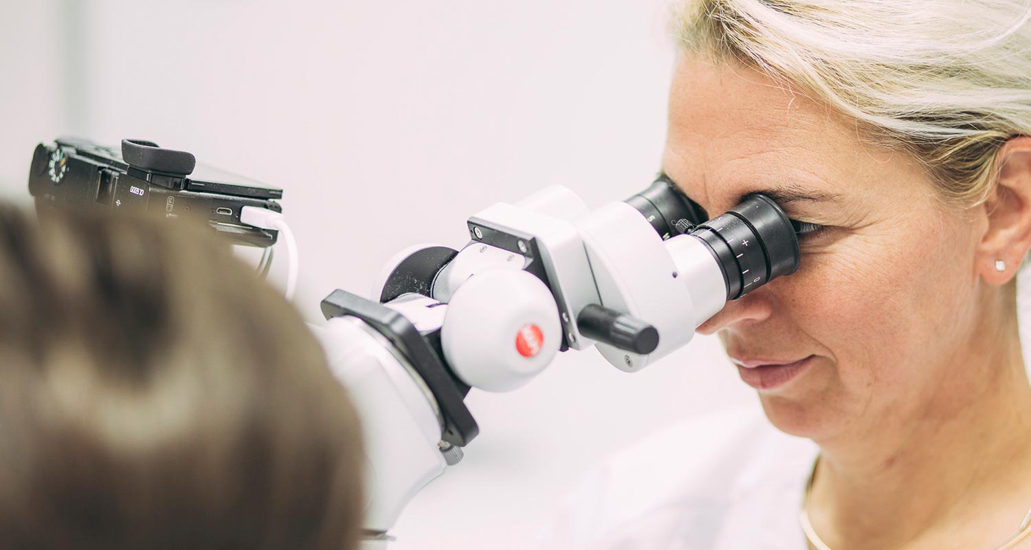 Dr. Carmen Pohl schaut durch Mikroskop