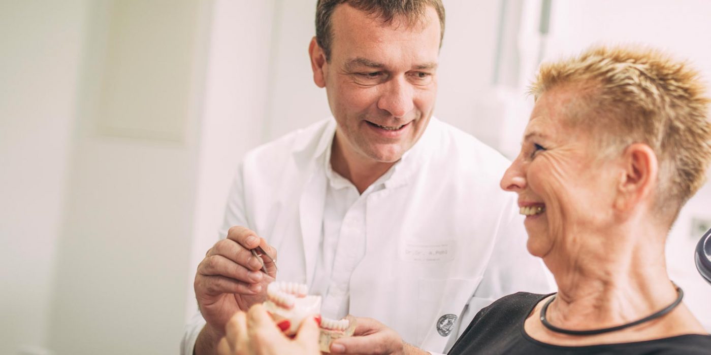 Dr. Andreas Pohl erklärt Patientin am Modell Zahnimplantate