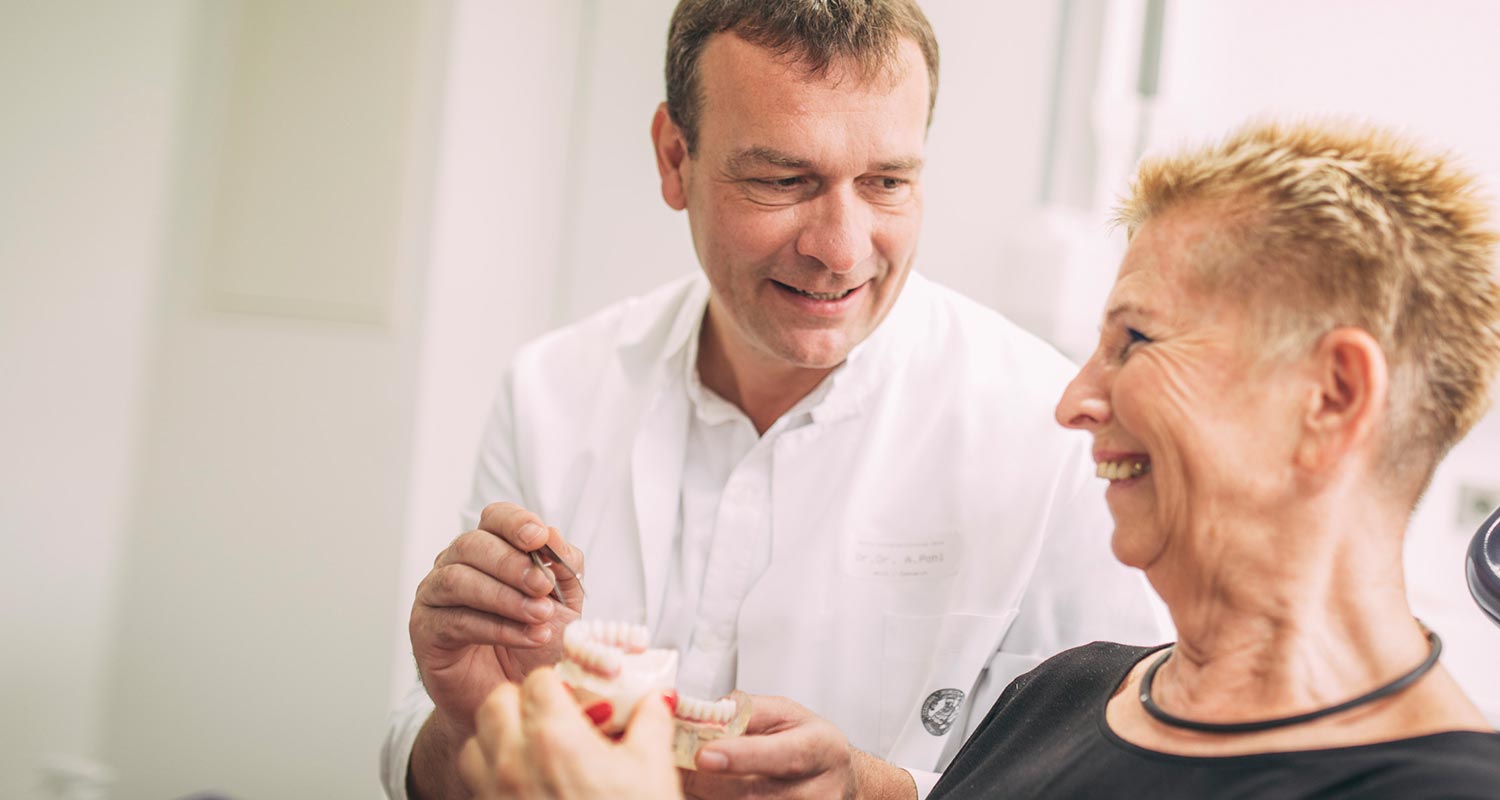Dr. Andreas Pohl erklärt Patientin am Modell Zahnimplantate